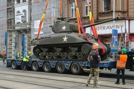 Jeřáb přenesl plzeňský tank Sherman přes střechu třípatrového domu