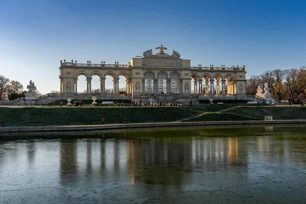 bezplatná Pohled na Gloriette v zámku Schönbrunn ve Vídni, odrážející se na rybníku pod jasně modrou oblohou. Základová fotografie
