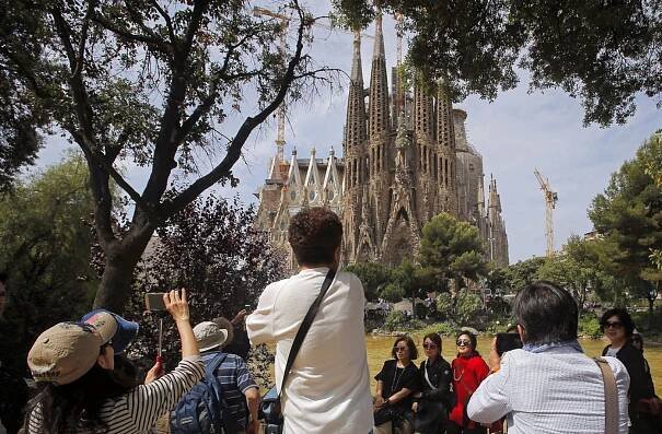 Tourists pose in front of Gaudí's Sagrada Familia in Barcelona on 26 May 2016. 