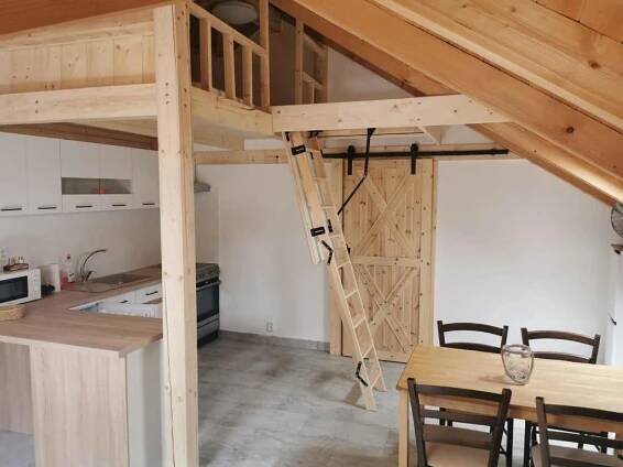 a loft bed in a kitchen with a table and chairs at Apartmány Nová duha Vavřinec in Vavřinec