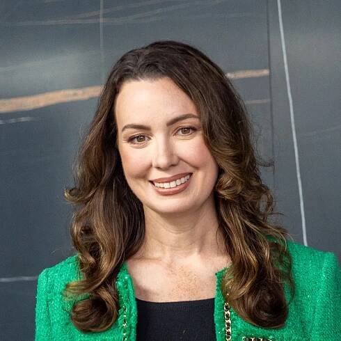 A woman wearing a green jacket is smiling for the camera