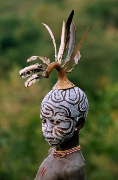 a statue with an elaborate headdress and feathers on it's head, in front of green grass