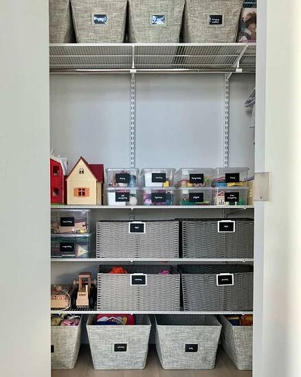Labeled baskets with toys in a storage closet