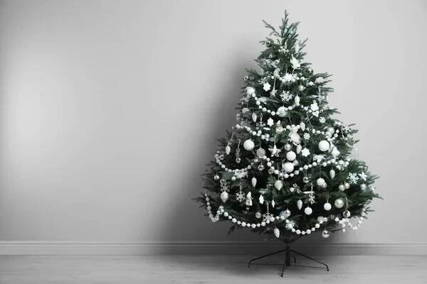 Beautifully decorated Christmas tree near light grey wall in room, space for text — Stock obrázek