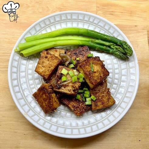 Marinated crispy tofu on a plate with asparagus
