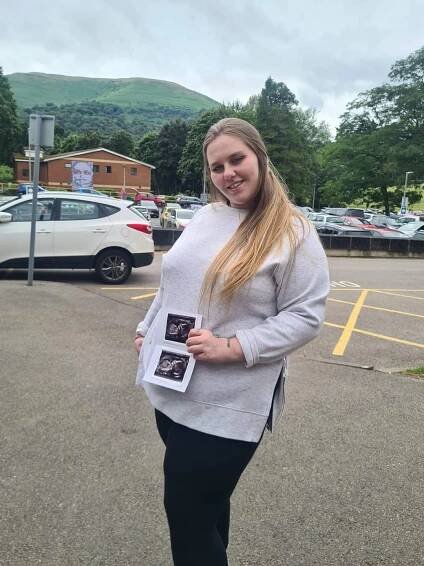 Pregnant woman holding ultrasound images.