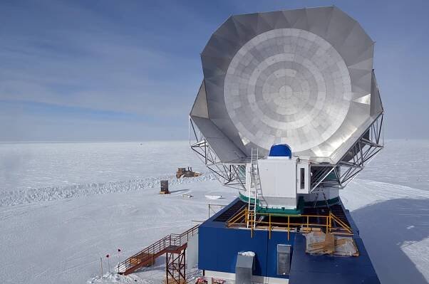 Image of a large silver dish against a blue sky surrounded by snow. 