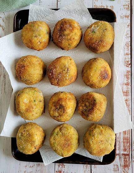 12 crispy arancini balls on a paper towel lined baking sheet