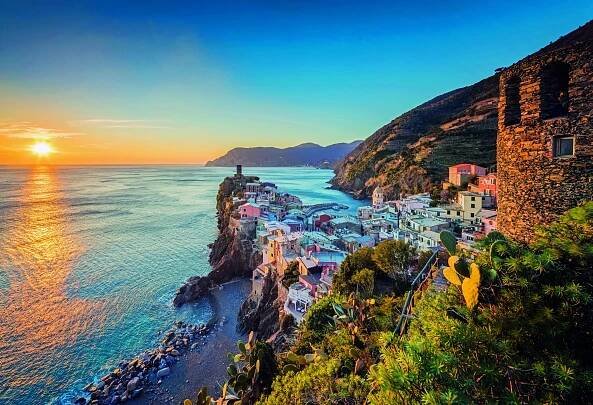 Picturesque sunset view of Vernazza, one of the five villages of Cinque Terre, Italy, featuring colorful cliffside houses overlooking the Mediterranean Sea.