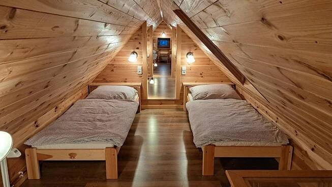 two beds in a room with wooden walls at Chalupa u Uhříků in Rajnochovice