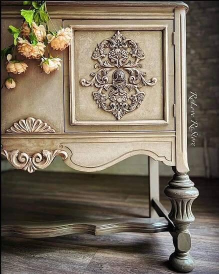 an ornate white cabinet with flowers on top