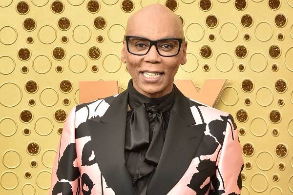 RuPaul in a colorful suit and glasses.