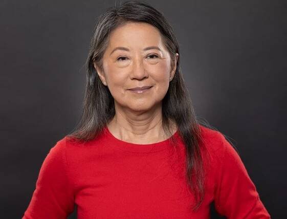 Ying-Hui Fu, who studies the genetics of familial advanced sleep phase trait, wears a red top and smiles against a grey background.