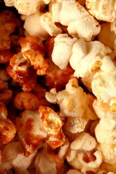 Close up photo of a bowl of two-tone popcorn: Maple White Cheddar Popcorn. Half of the popcorn is covered with maple caramel, the other half is white - white cheddar.