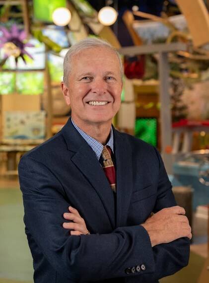 Doug Jones standing with arms folded in front of Discovery Zone exhibit