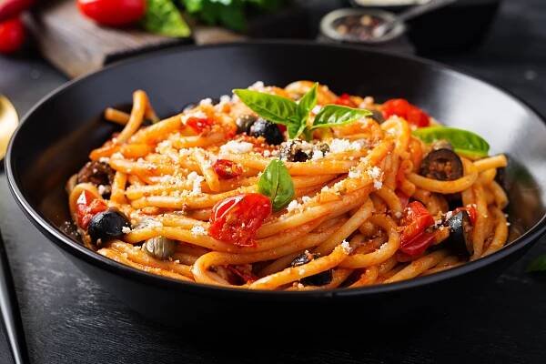 špagety alla puttanesca - italské těstoviny s rajčaty, černými olivami, kapary, ančovičkami a basi - spaghetti - stock snímky, obrázky a fotky