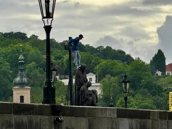 Zásah policie na Karlově mostě kvůli muži, který s nožem vylezl na sochu a hrozí sebevraždou
