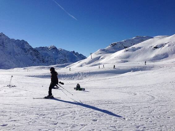 a person riding skis on top of a snow covered slope with mountains in the background