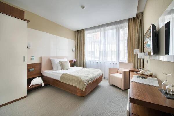 Wellness Hotel Diamant Hluboká nad Vltavou Exterior photo The photo shows a cozy hotel room with a comfortable bed as the focal point. The bed has a light pink headboard and footboard, and is neatly made with white linens and a light beige bedspread with a subtle pattern. Two pillows, one white and one ligh