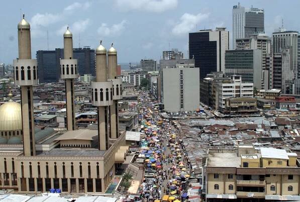 People and traffic move along a busy street in Lagos.