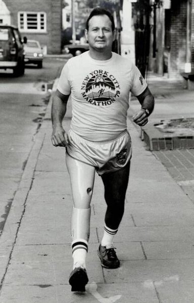 A black-and-white photo of Dick Traum in running shorts and a T-shirt that reads “New York City Marathon ’79.” 