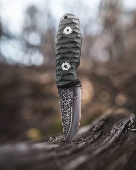 A bushcraft knife stuck in a piece of wood