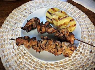 chinese chicken on a stick serv ed on a white plate with grilled pineapple