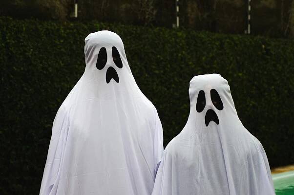 bezplatná Dva lidé oblečení jako duchové v bílých prostěradlech se smutnými tvářemi venku. Ideální pro halloweenská témata. Základová fotografie