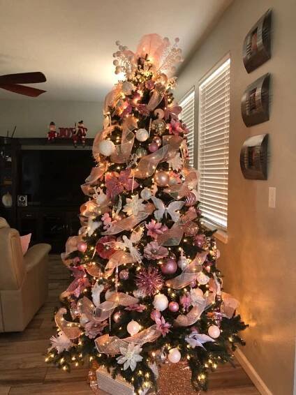 a decorated christmas tree with pink and white ornaments in a living room next to a window