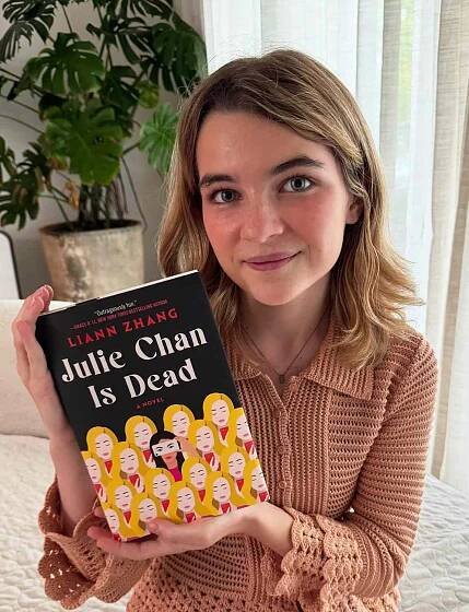 Raegan Revord holding a copy of 'Julie Chan is Dead' by Liann Zhang