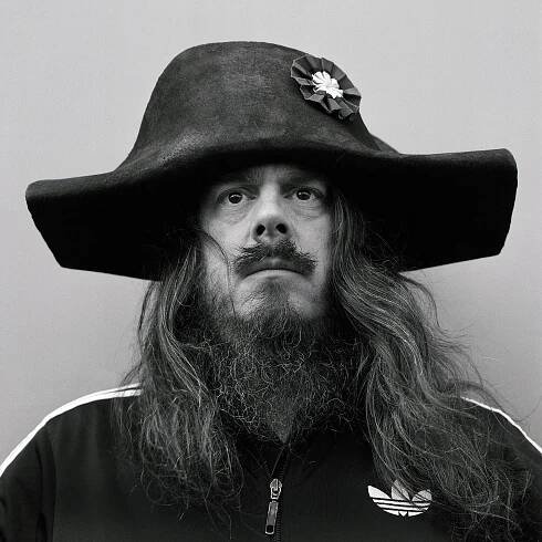 Jonathan Meese wearing black Adidas tracksuit and a felt bicorne.