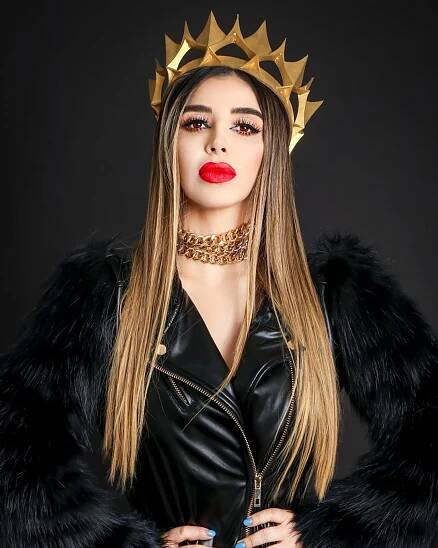 Portrait of Emma Coronel Aispuro wearing a gold crown and black leather jacket.