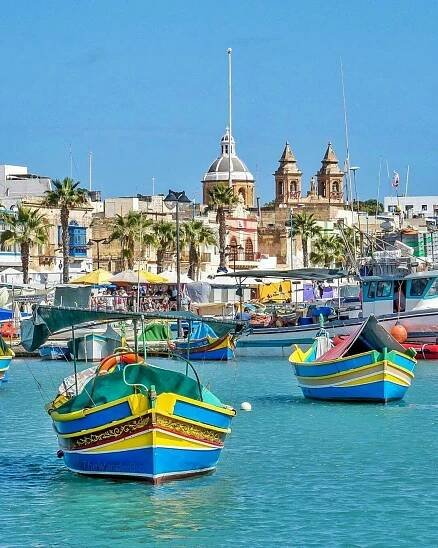 many small boats are in the water near some buildings and palm trees on the shore
