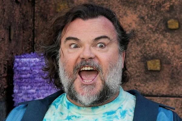 Jack Black, in a tie-dye shirt, opens his mouth and eyes wide.