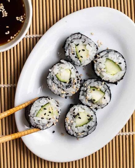Taking a piece of kappa maki out of a plate with a plate of soy sauce beside.