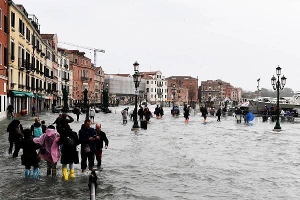 Touristen waten durch das überflutete Venedig
