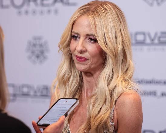 Sarah Michelle Gellar with long hair in a patterned dress being interviewed on the red carpet