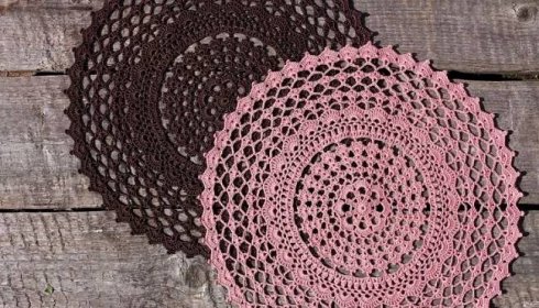 two crocheted doily sitting on top of a wooden table