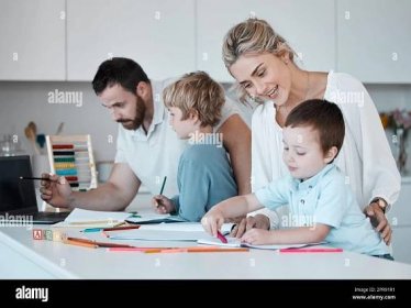 Young caucasian family homeschooling their two children. Loving parents helping their little children with homework. Mom and dad teaching kids to write, read and draw Stock Photo