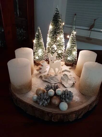some candles are sitting on a table with pine cones and christmas trees in the background