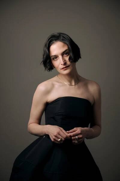 A woman with short black hair in a black strapless dress with her hands in front of her waist.