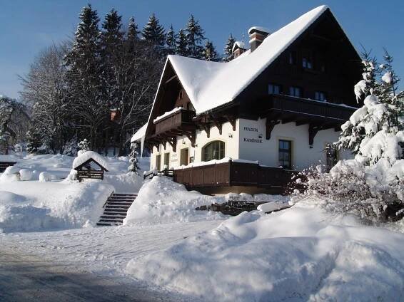 a man standing on the roof of a house covered in snow at Penzion Kamínek in Janske Lazne