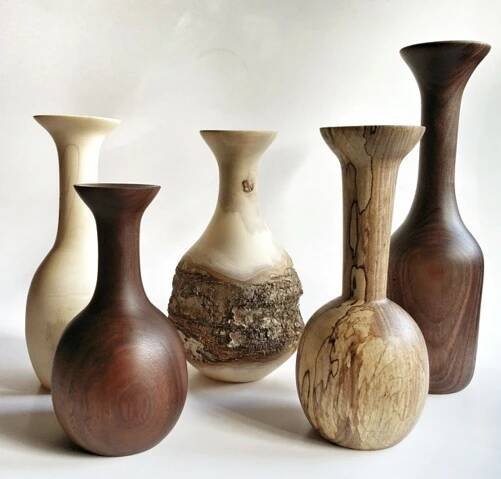 five vases are lined up on a white surface