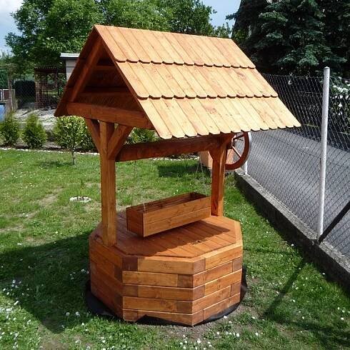 a small wooden structure with a roof in the grass