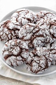 Several chocolate crinkle cookies with cracked surface and coated in powdered sugar.