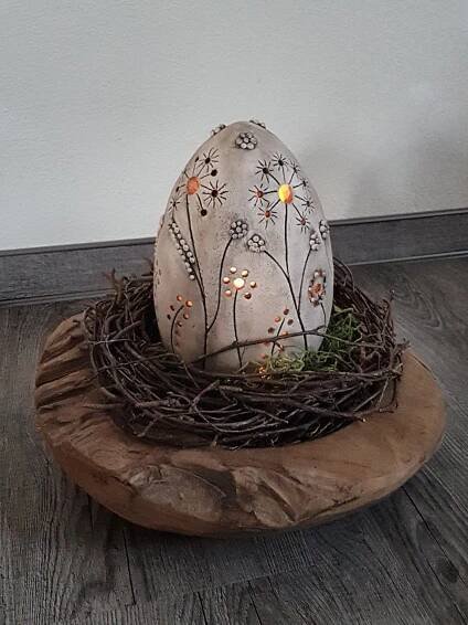 an egg sitting on top of a nest with flowers and lights in the eggshell