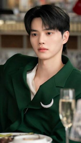 a young man sitting at a table with a glass of wine in front of him