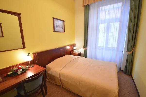 a hotel room with a bed and a desk and a window at Grandhotel Garni in Jihlava