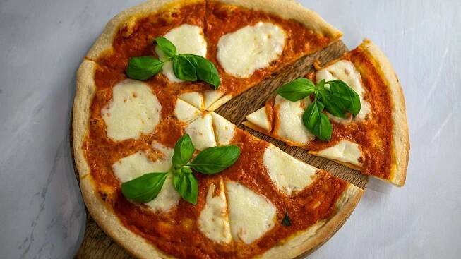 Domácí pizza Margherita s rajčaty, mozzarellou a bazalkou je italská klasika