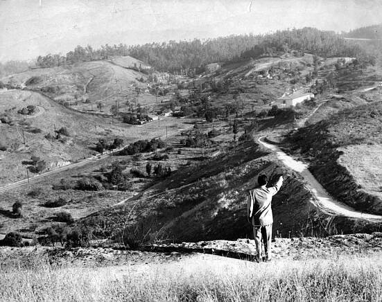 October 7, 1957: A Herald-Examiner reporter points out the future location of home plate at Dodger Stadium. The Los Angeles Police Academy can be seen in the far background. Courtesy of the Los Angeles Public Library